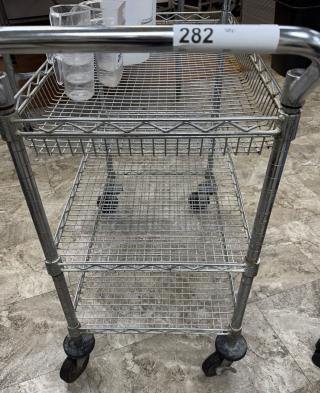 Rolling wire cart with three shelves, silver finish, sturdy metal frame, swivel casters, auction tag 282 visible.