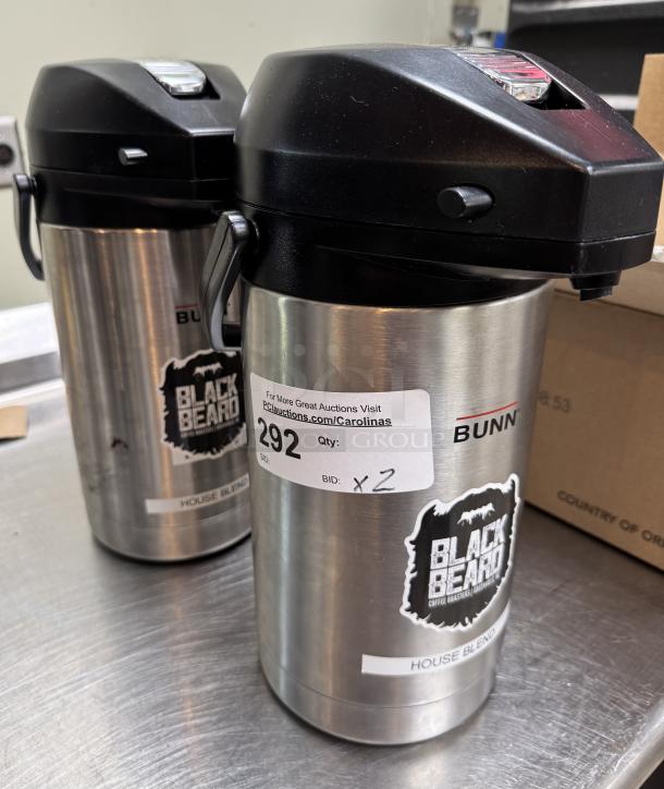 Bunn coffee dispensers, Blackbeard branding, stainless steel, batch of 2. Labels show auction info and bid quantity.