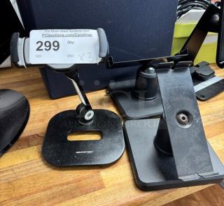 Three AboveTEK iPad holders on wooden surface, including base plates and adjustable arms. Visible label reads "299, Qty: x3".