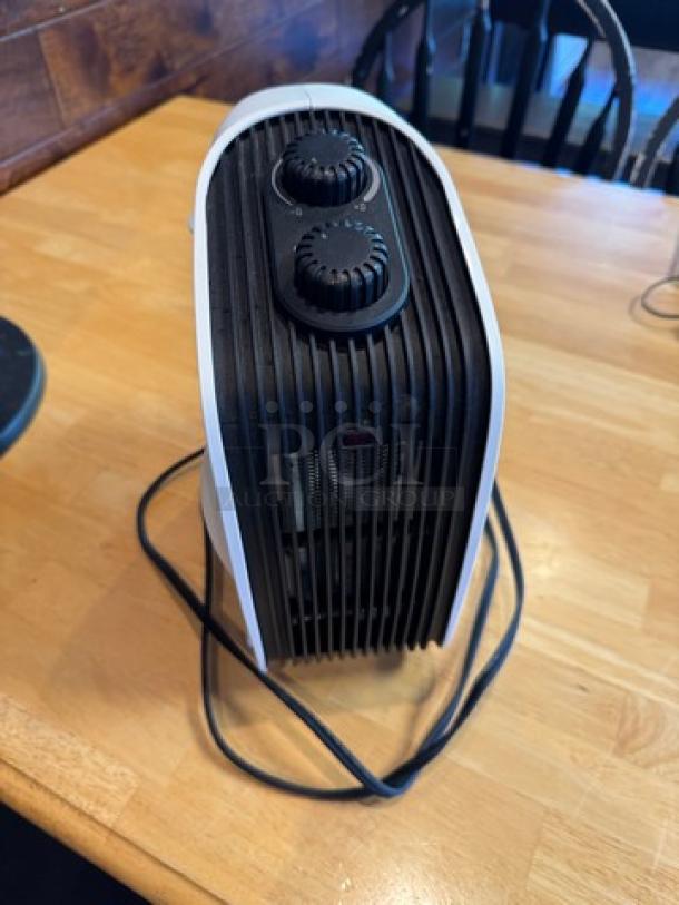 Honeywell portable heater, black with white trim, dual dials, tested and working, cord attached, on a wooden surface.