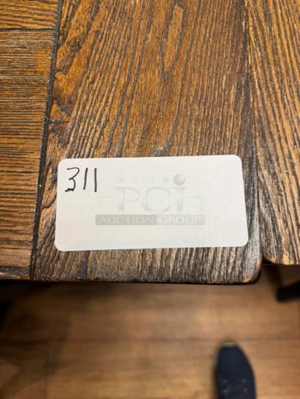 Wooden dining table with rich grain pattern and visible tag labeled "311". Appears in excellent condition with smooth finish.