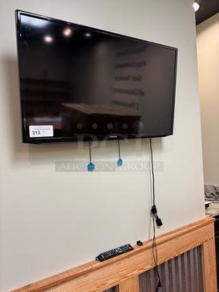 Samsung 42" TV mounted on wall, includes remote control. Tested and working. Auction tag visible.