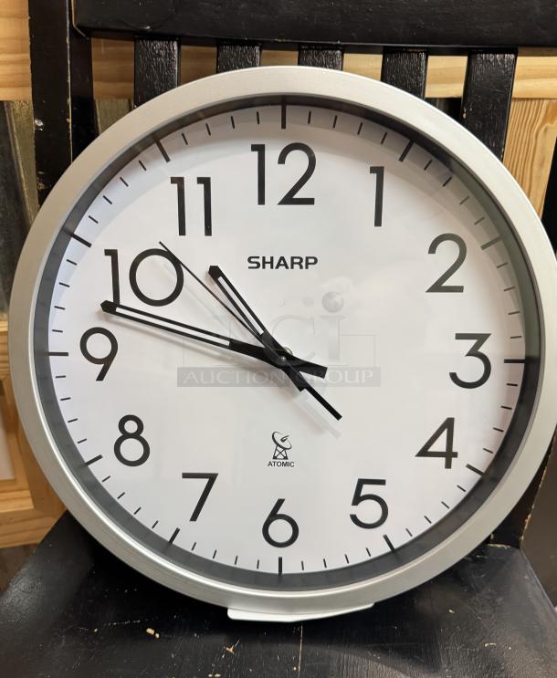 Sharp wall clock with silver frame and bold black numbers, “Atomic” label, tested and working, white face, excellent condition.