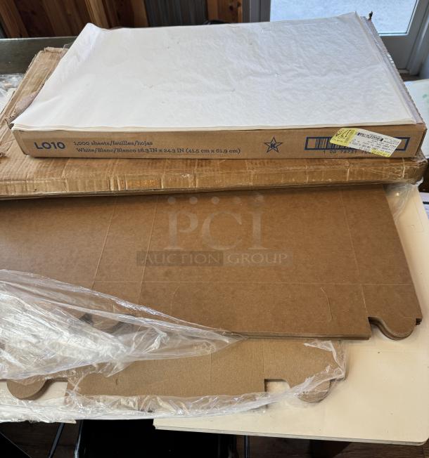 Assorted bakery supplies including boxes, parchment paper (1,000 sheets, white, 16.3x24.3 in), and bags. New condition.