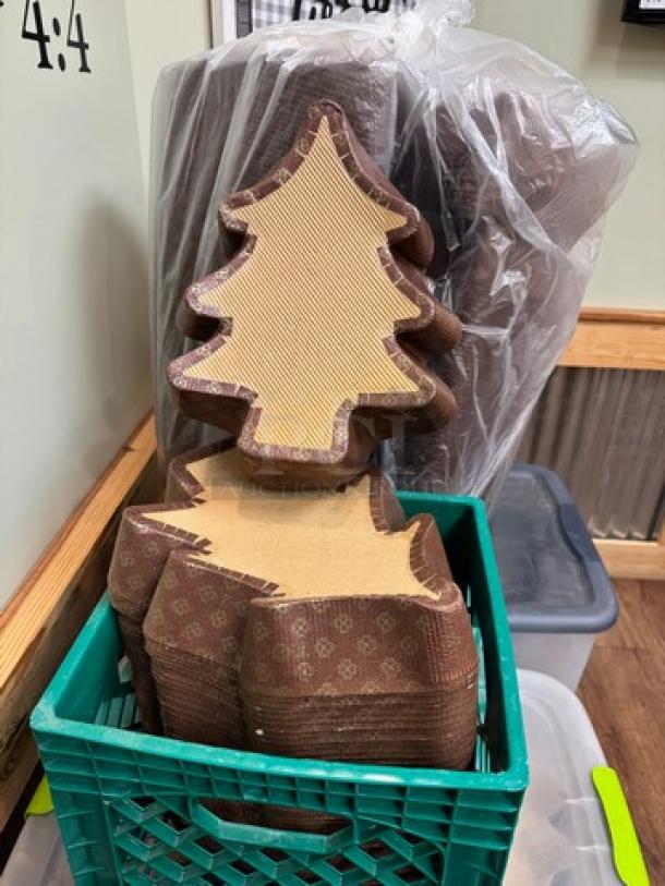 Christmas tree-shaped baking molds, stack of two, made from brown paper with decorative patterns. Stored in a green crate. Ideal for holiday baking.