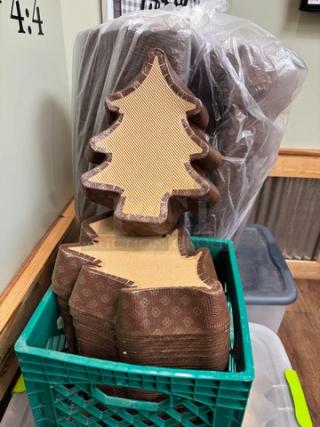 Christmas tree-shaped baking molds, stack of two, made from brown paper with decorative patterns. Stored in a green crate. Ideal for holiday baking.