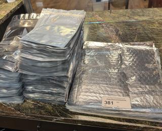 Foil liners, sealable bags in bulk, displayed stacked. Tag shows lot number 381. Ideal for preservation or storage.