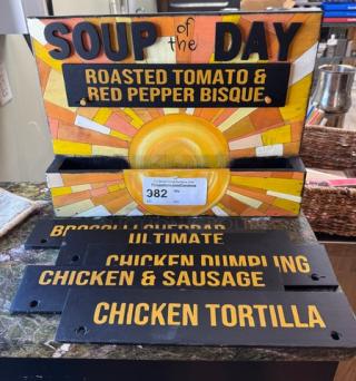 Wooden "Soup of the Day" display with sunburst design, featuring "Roasted Tomato & Red Pepper Bisque" sign. Includes interchangeable soup labels.