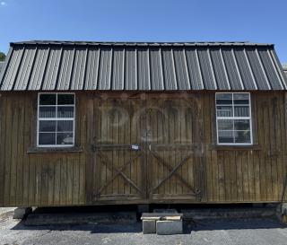 Outside wood barn with metal roof, featuring two windows. Barn is in good condition, with visible tag on door.