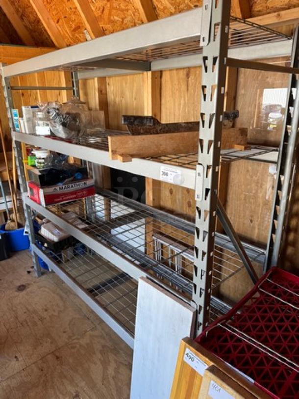 Metal rack with 4 wire shelves, sturdy steel frame, in used condition. Ideal for storage, with some items displayed.