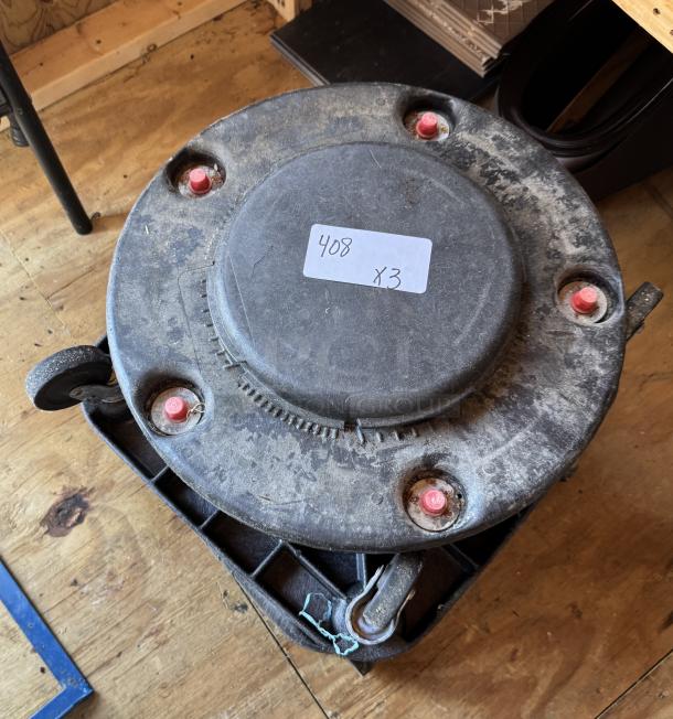 Trash can dolly in used condition, visible dust and wear, with four red caster attachments. Label reads "408 x3."
