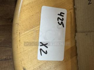 Round wooden dining table corner with visible smooth finish. Auction tag marked "425 x2" indicating bid information.