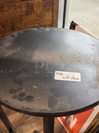 Black round table with visible wear, paired with two stools. Label reads "426 w/2 stools." Suitable for casual settings.