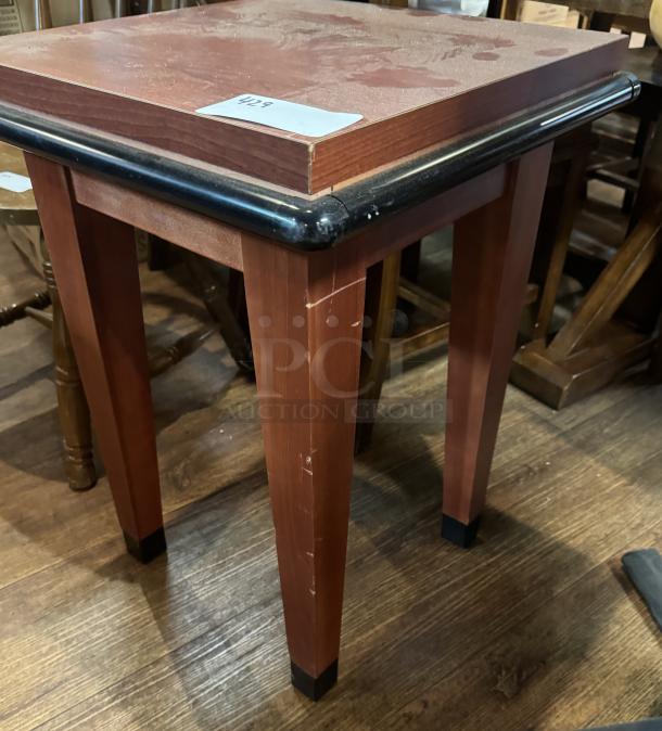 Wooden display table with black trim, square top, tapered legs, minor surface wear, auction tag with number 428.
