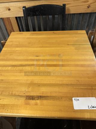 Wooden dining table with natural finish and two black chairs. Slight wear visible. Tag shows "432" indicating item number.