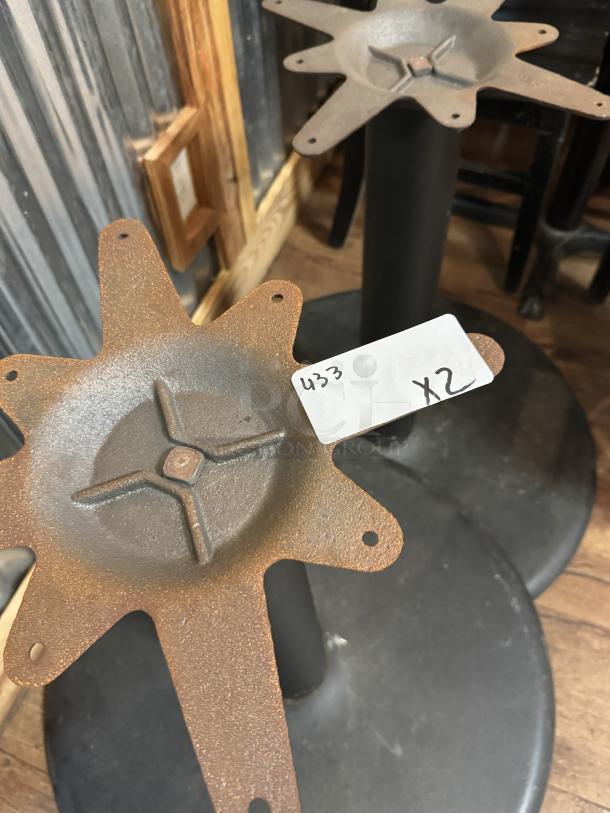 Two metal table bases with a star-shaped top design. Each base has a rustic finish. Tag reads "433 x2".