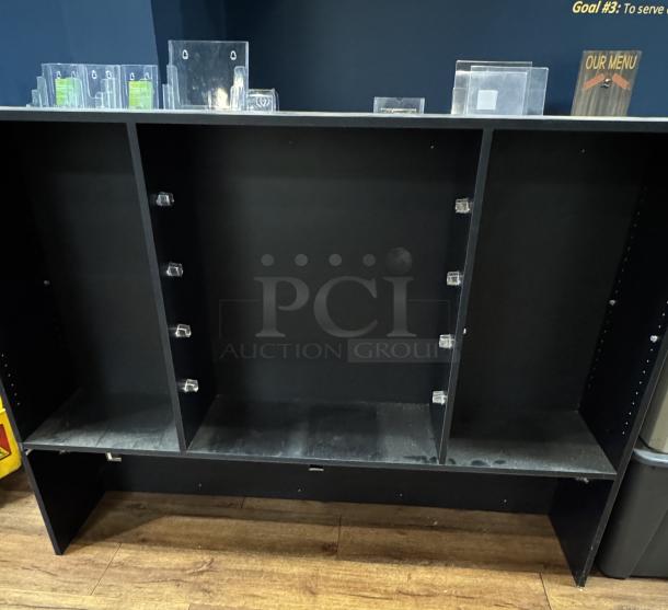 Black display case with three sections, multiple adjustable shelves, and a sturdy wooden construction. Some dust visible.