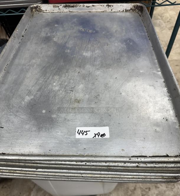 Full-size sheet pans, stack of 9, showing signs of wear. Label reads "445 x9". Suitable for commercial baking.
