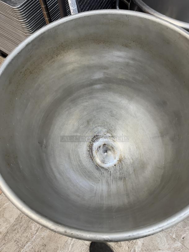 Steel 140 qt. mixing bowl with light wear, scratches, and patina; includes a dollie for mobility. Ideal for commercial use.