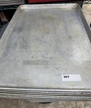 Full size sheet pans, set of 9, used condition with visible wear. White label marked "447" on top pan.