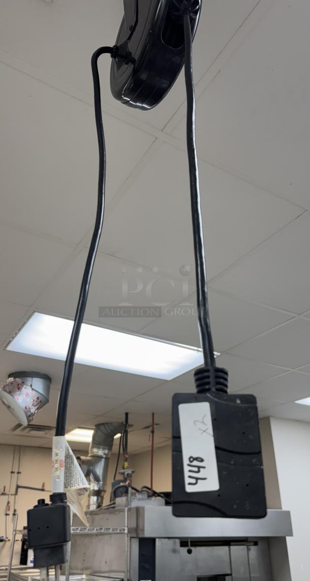 Pro Reel ceiling drop cords, black, two outlets visible, used condition. Marked with handwritten tag "x2 8hh". Ceiling-mounted.