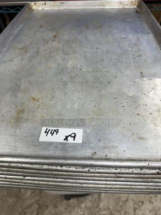 Full size sheet pans stack, moderate wear, labeled "449 x9," metal construction, suitable for commercial baking.