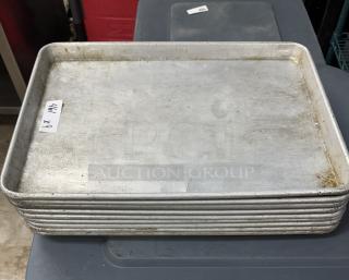 Stainless half-size sheet pans, stack of 9, used condition, visible label "9 x". Ideal for baking, sturdy design.