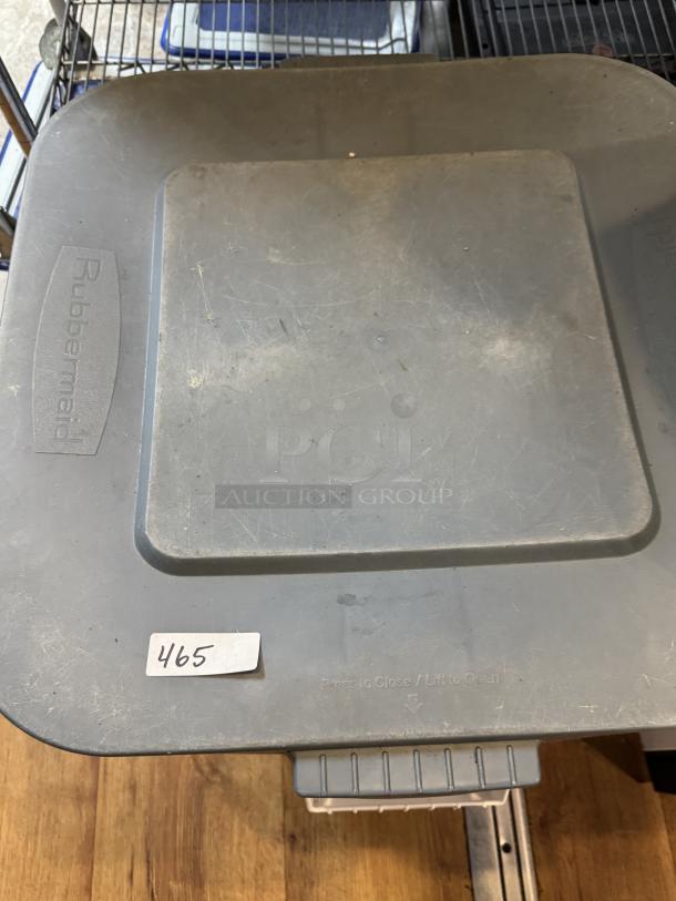 Rubbermaid 28 Gal. dry storage container, gray, used condition. Visible logo and "Press to Close / Lift to Open" text. Label "465."
