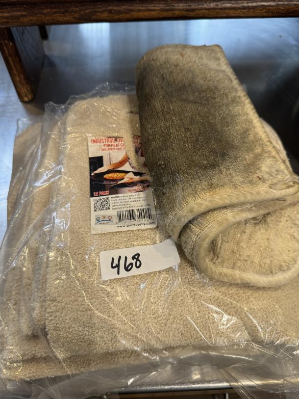 Industrial hot oven pads, 12-pack, beige, used condition. Packaging shows label with safety info and barcode.