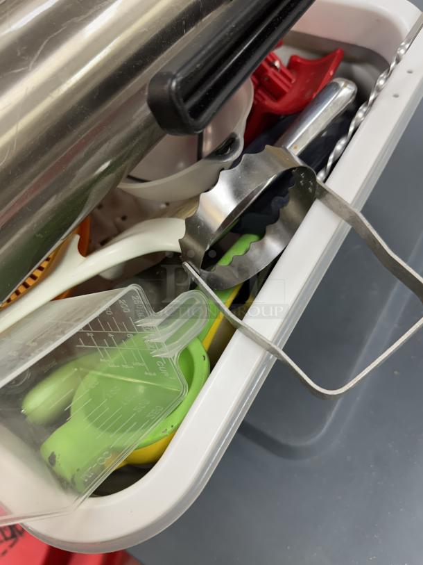 Assorted kitchen utensils with two collapsible dish racks, includes a measuring cup, metal whisk, and colorful items, in good condition.