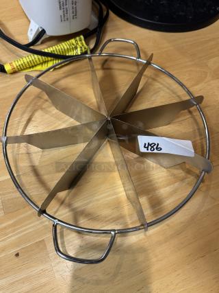 Stainless steel pie cutter with 8 segments, two side handles, and a numbered tag marked "486," in good condition.