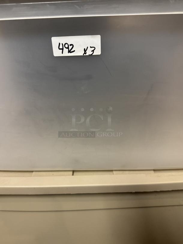 Large plastic storage totes, stackable, durable, auction lot of 3. Label reads "492 x 3." Ideal for organizing items.