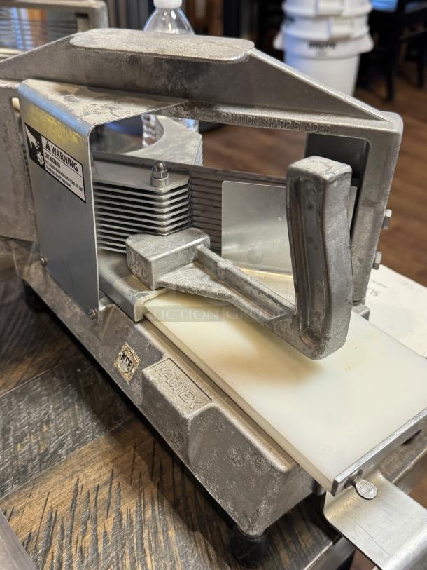 Nemco slicer with new blades, metal construction, caution label, sturdy design, textured surface, includes KATEX branding.