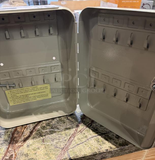 Key box with hooks, open to show interior. Beige metal, multiple hooks for keys. Label with mounting instructions visible. Excellent condition.
