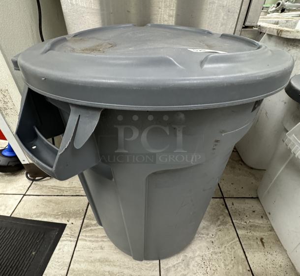Rubbermaid trash can with lid, gray, sturdy plastic, side handles, minor wear, ideal for commercial use.