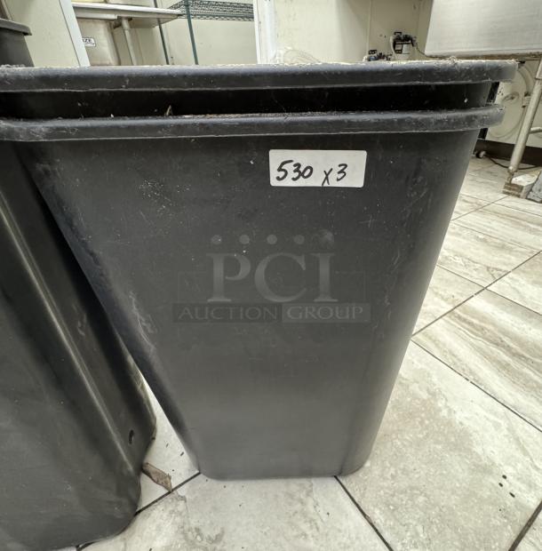 Black trash cans, set of three. Durable plastic construction, label reads "530 x 3," indicating quantity in good condition.
