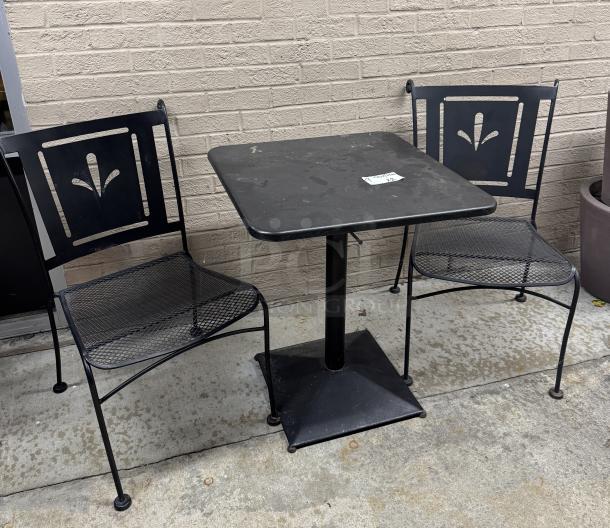 Metal table with square top and two chairs featuring decorative backs. Black finish, good condition. Visible sticker: "2".