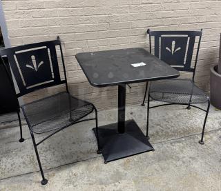 Metal table with square top and two chairs featuring decorative backs. Black finish, good condition. Visible sticker: "2".