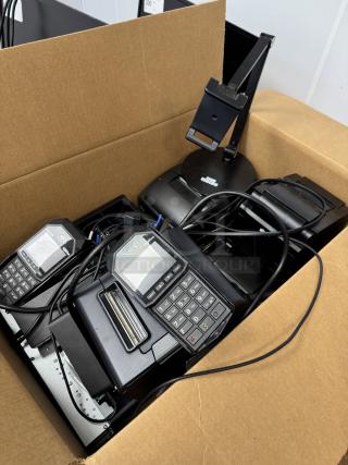 Box of assorted cables, printers, cash drawer, and payment terminals with visible wires. Items appear used.