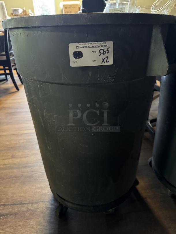 Large gray trash can on dolly, slight wear, label indicating lot 565 for auction, quantity of 2, sturdy condition.