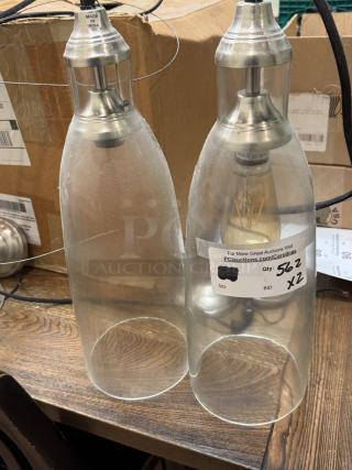 Pair of hanging pendant lights with glass shades and silver metallic fixtures. "Made in India" label visible. Condition appears used.