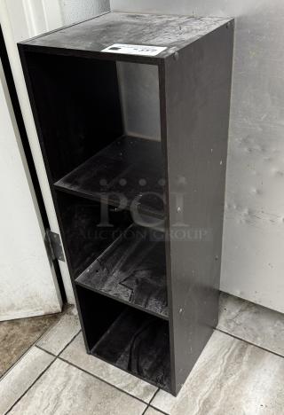 Black bookcase with 3 shelves, used condition, surface dust visible. Compact size, ideal for small spaces.