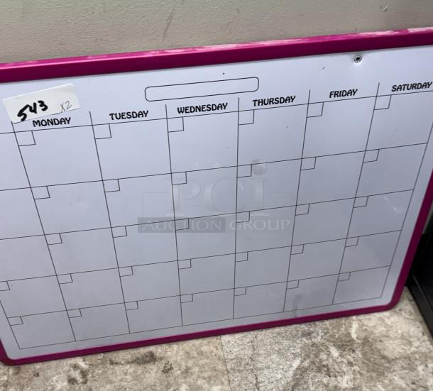 Wall mount monthly planner with pink frame, grid layout for days of the week. Label indicating "543 x2" present. Good condition.