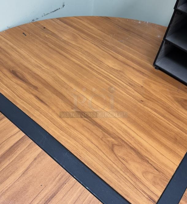 Wooden corner office desk with a polished surface and minor scratches, featuring black trim and a corner storage shelf.