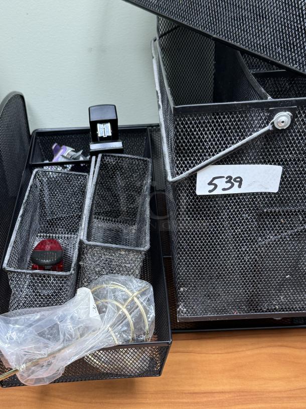 Metal mesh desk organizer with trays and baskets. Includes several compartments, office supplies, and a visible tag marked "539."