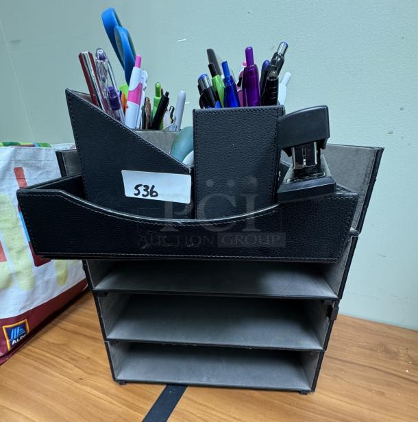 Black leather desk organizer and tray with assorted pens, stapler, and office items. Label reads "536." Four-tier tray structure.