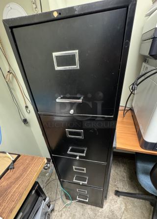 Black 4-drawer filing cabinet, metal, with label holders and silver handles. Used condition with minor surface wear.