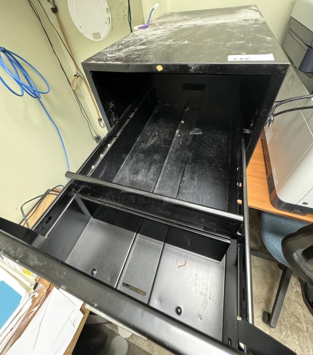 Black 4 drawer filing cabinet, open top drawer shown. Visible scratches and wear indicate used condition.