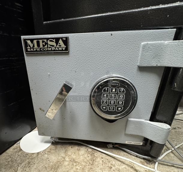 Mesa Safe with combination lock, metal finish, minor wear on exterior, branded plate and keypad visible.