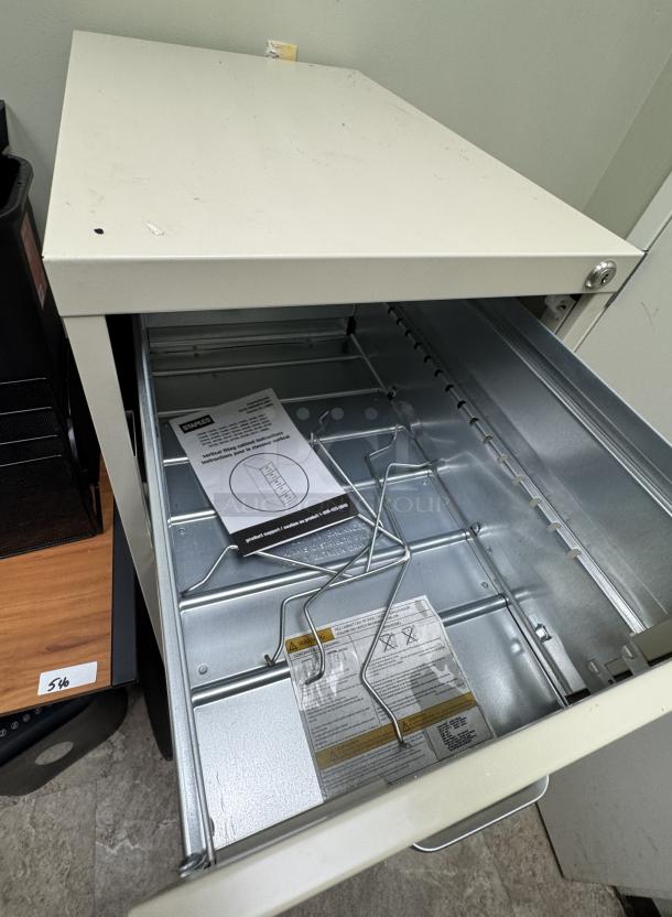 4-drawer filing cabinet, beige, lacks key. Metal construction, signs of wear, includes labels and instructions inside drawer.